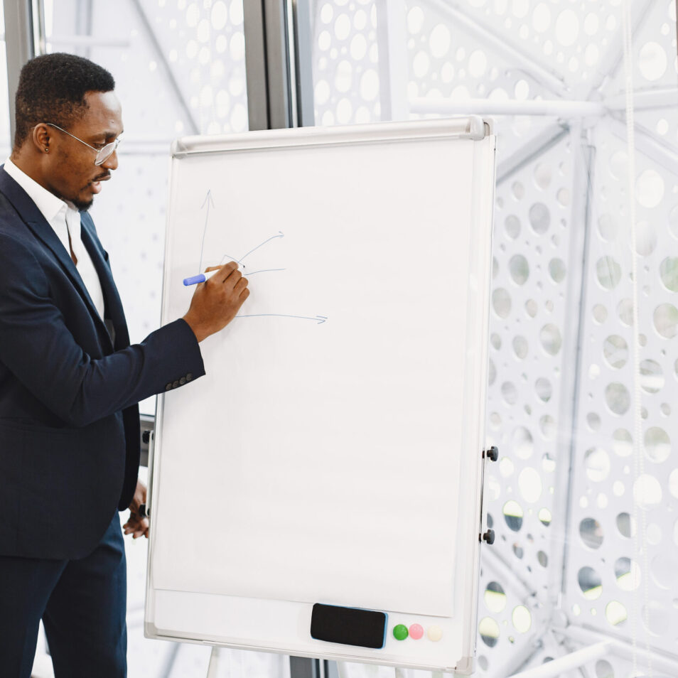 African man in a black suit. Writing board. Guy do presentation.